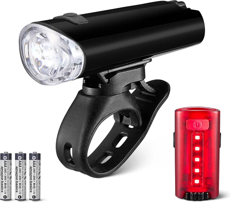 Amazon Basics ▫️ Conjunto de luzes LED para bicicleta com farol de 100 lúmenes e luz traseira de 10 lúmenes - Luzes de bicicleta à prova de água com 3 modos e suportes - Pilhas incluídas - Preto e vermelho